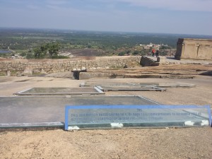 The photo shows a rock mountaintop on a gentle slope down away from the camera. There are several glass covers patching the face of the rock, and a sign reads "396. This inscription dated chitra su.5 of saxa 1574 cooresponding to 4th March 1652 AD refers to the pilgramage of Jagasa and Gonasa Samasani.