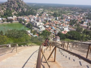 The photo shows a long, long line of steps carved into a granite rock face. At the bottom of the steps is a city.