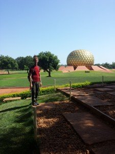 Mikey stands smiling in front of the Matrimandir in Auroville