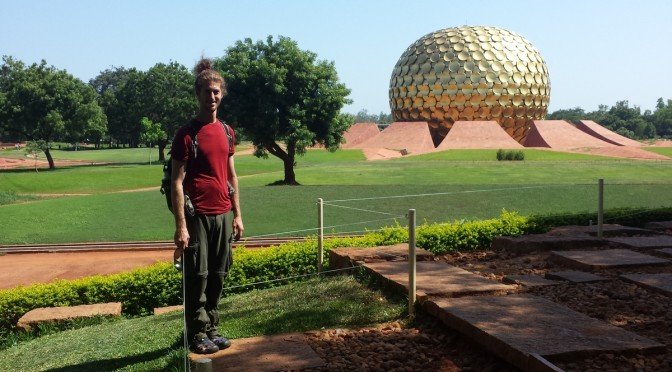 Mikey stands smiling in front of the Matrimandir in Auroville