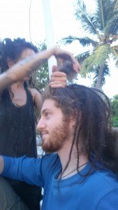 Mikey's hair is being dreaded by Vera. She is almost finished in this photo.