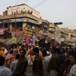 A crowd of people fill a street celebrating Krishna.