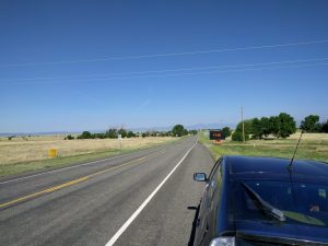 Mikey's car is parked on the shoulder; in front of him a sign reads "FIRE" in big, orange letters. In the distance there are mountains.