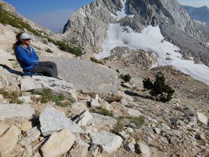 Mikey sits, admiring the Hoover Wilderness. Behind him is a mountain pass.