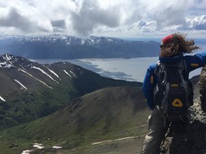 Mikey stands on an mountain in Alaska on McHugh Peak overlooking the ocean