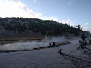 Mikey's bicycle is parked next to a large pool of water that is emitting hot steam