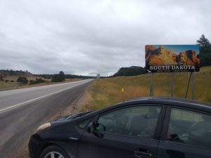 A sign reads "Welcome to SOUTH DAKOTA. GREAT FACES. GREAT PLACES."