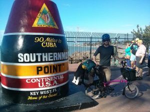 Mikey stands next to a giant monument that reads "The Conch Republic. 90 Miles to CUBA. SOUTHERNMOST POINT. CONTINENTAL USA. Key West, FL. Home of the Sunset."