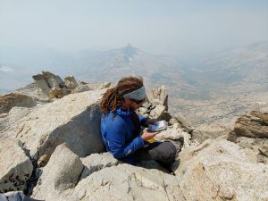 Mikey is sitting atop the peak of Matterhorn looking through the summit log