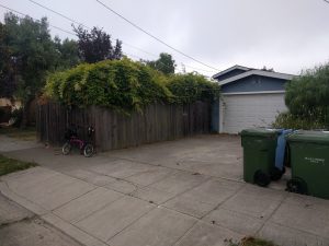 Mikey's bicycle is leaned against a fence next to a house.