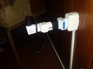 A usb cable dangles from an inverter which is plugged into a European-to-US adapter which is plugged into a E/F-to-C converter which is plugged into a 3-way splitter which is plugged into a power outlet