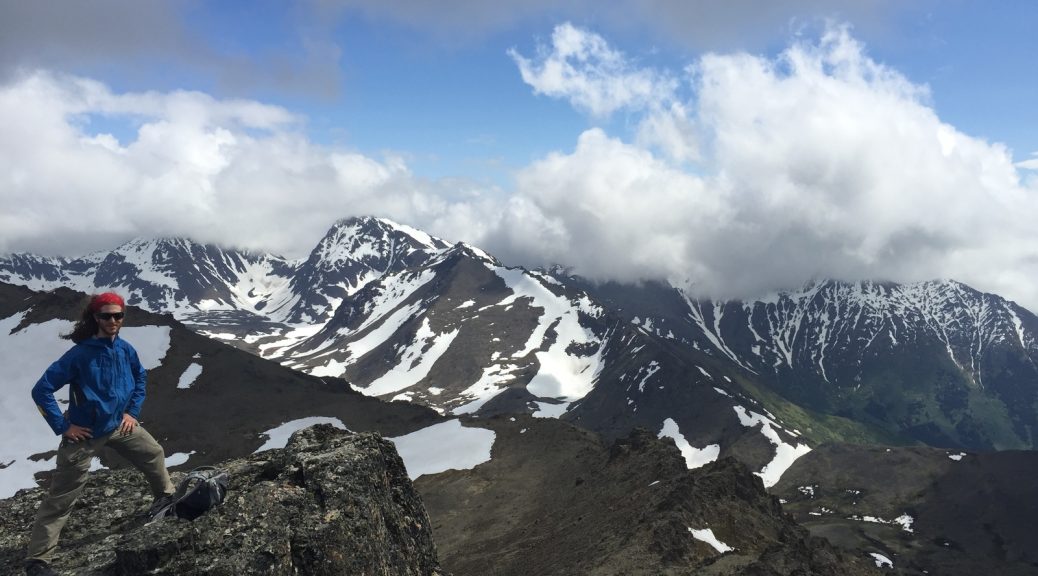 Mikey stands on an mountain in Alaska on McHugh Peak