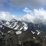 Mikey stands on an mountain in Alaska on McHugh Peak