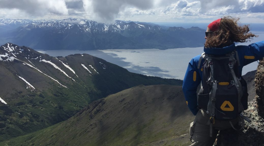 Mikey stands on an mountain in Alaska on McHugh Peak overlooking the ocean