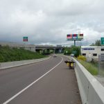 Mikey's bicycle is in the shoulder leaned up against a concrete barrier. A sign reads "ENTERING EUGENE"
