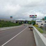 Mikey's bicycle is in the shoulder leaned up against a concrete barrier. A sign reads "ENTERING EUGENE"