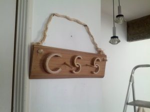 A bamboo sign hangs on the wall from a rope. It reads "CSS"