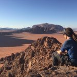 Mikey sits atop a sandstone mounain overlooking their bedouin camp in Wadi Rum