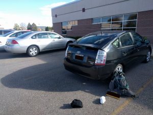 Mikey's car is parked. His New York plates are leaned against his backpack next to the car. The car has new plates that read "WISCONSIN"