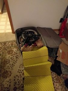 Mikey's Brompton bicycle is folded up and placed inside of a suitcase.