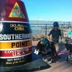 Mikey stands next to a giant monument that reads "The Conch Republic. 90 Miles to CUBA. SOUTHERNMOST POINT. CONTINENTAL USA. Key West, FL. Home of the Sunset."