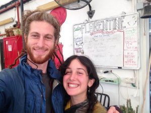 A & Mikey smile for a selfie in front of a sign that reads "Florentine Backpacker's Hostel"