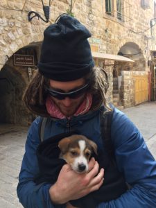 Mikey, smiling, holds a small puppy wrapped in a blanket.